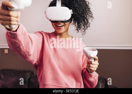 Young African American female in VR goggles and with joysticks experiencing augmented reality Stock Photo
