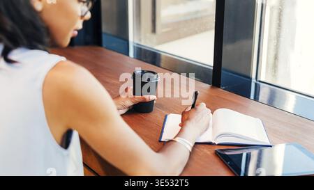 Young entrepreneur taking notes in cafe Stock Photo