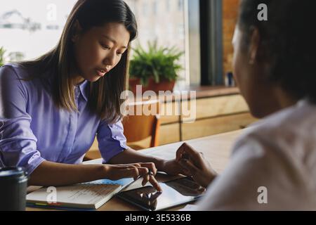 Two graphic designers sitting at a table, working on digital tablet Stock Photo