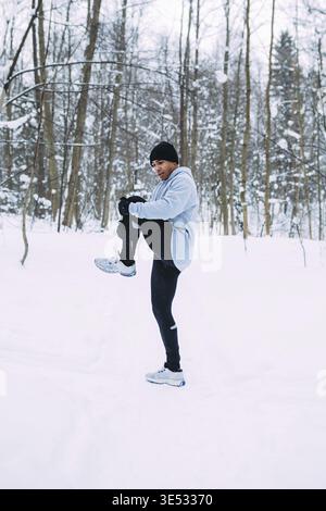 Male athlete doing stretching exercises. Fit male warming up outdoors Stock Photo