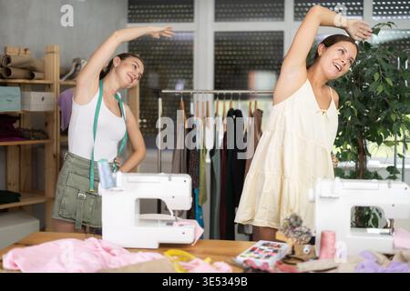 Female dressmakers doing a warm-up in the workshop in summer Stock Photo