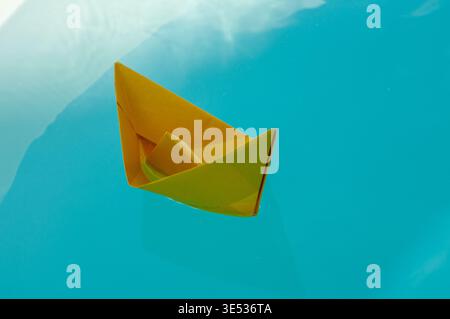 paper boat floating on calm blue water with copy space, concept of journey and progress Stock Photo