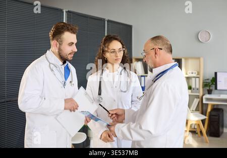 Medical colleagues discussing patient charts in collaborative clinic briefing Stock Photo