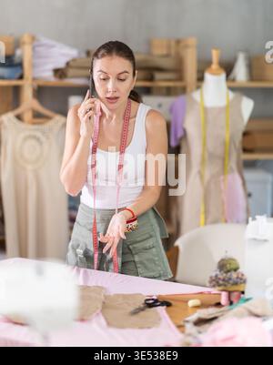 Angry seamstress is talking on phone Stock Photo