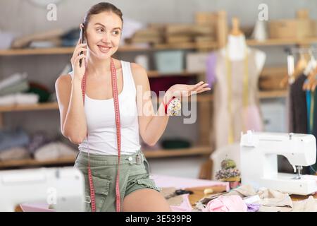 Female fashion designer talking on phone in workshop Stock Photo
