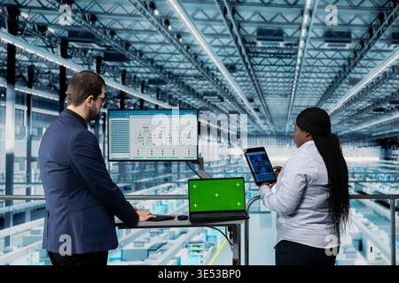 Green screen laptop, designing microchip layout and hardware developers using EDA program in industry 4.0 plant. Reviewing automated semiconductors smart factory schematic, mockup notebook and workers Stock Photo