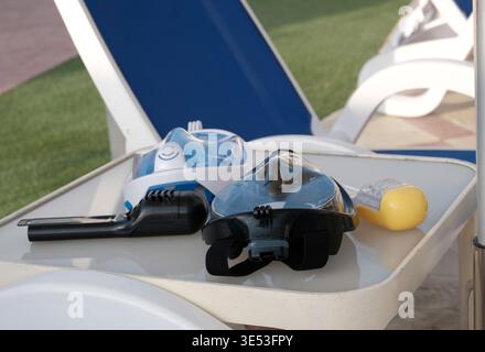 Full face snorkeling masks on table by beach loungers. Stock Photo