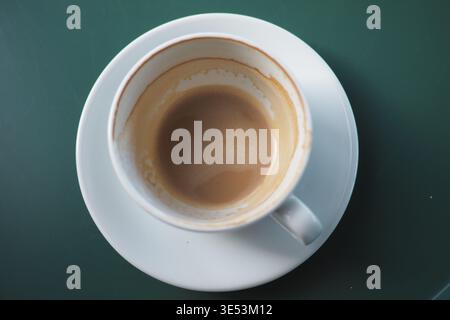 Coffee cup on a white plate with a dark green background Stock Photo