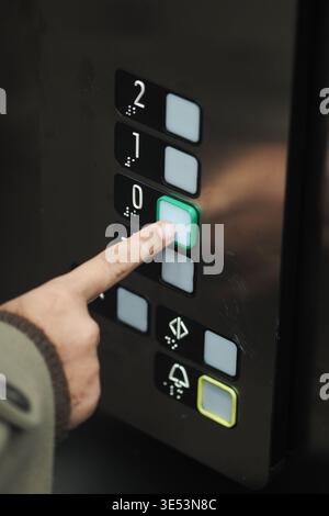 Person presses button in an elevator to go down Stock Photo