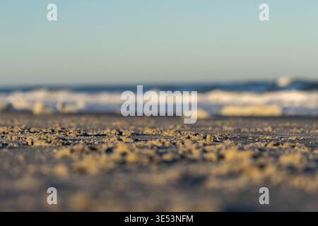 Macro Texture of Sandy Beach with Blurred Ocean Waves at Golden Hour Stock Photo