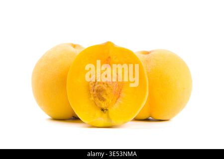Yellow peaches, one sliced in half, presenting fresh, juicy fruit against a white background Stock Photo