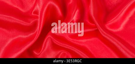 Red satin fabric showing elegant smooth folds and vibrant texture Stock Photo