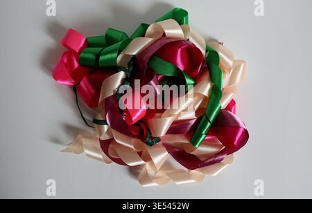Group of ribbons in different colors sits on a white surface. The ribbons are curled and twisted, ready for use in craft projects or decorations. The Stock Photo