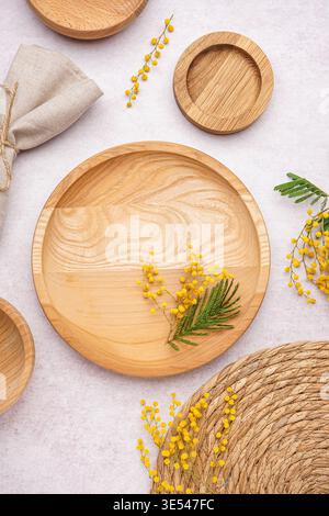 Composition with clean wooden dishes, napkin and mimosa flowers on white grunge table Stock Photo