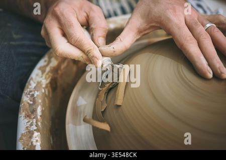 Creative, hands and tool with potter in clay workshop for manufacturing or production of ceramics. Mud, process and small business with person in Stock Photo