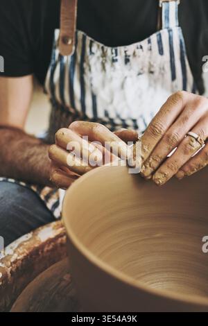 Clay, hands and process with person in pottery workshop for manufacturing or production of ceramics. Creative, small business and tool with artisan in Stock Photo