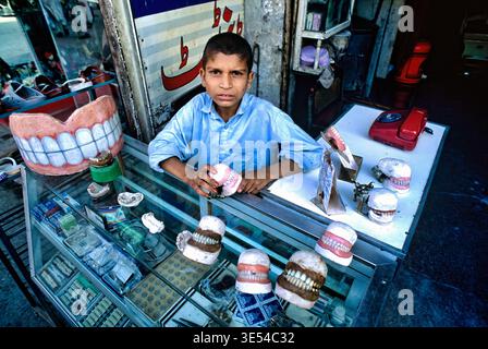 A street dentist is working in Peshawar. He shows dental models and tools to potential patients in his small shop. Stock Photo