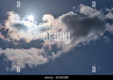 A beautiful natural phenomenon of cloud iridescence or irisated clouds near the sun. Rare rainbow colors visible on the edges of clouds against a deep Stock Photo