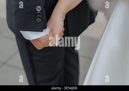 Close-up of couple holding hands outdoors. Romantic gesture symbolizing love, support, and partnership. Perfect for wedding and relationship concepts. Stock Photo