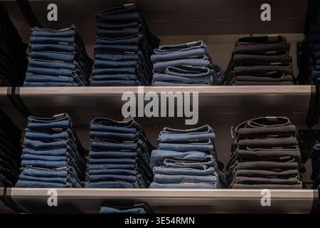 Stacked jeans on shelves in clothing store retail fashion shopping concept Stock Photo