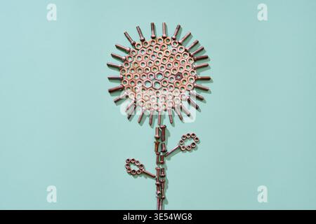 Metal bolts and nuts arranged as abstract flower shape on mint background in minimal style Stock Photo