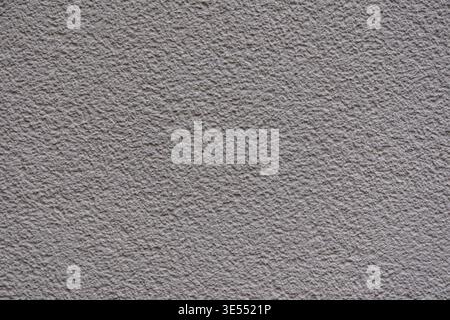 Close up of rough gray plaster surface with fine granular texture. Abstract construction background with uneven stucco pattern and neutral tones. Stock Photo