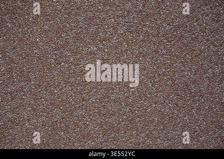 Close up of dense red gravel surface with fine granular structure. Natural stone background with uniform pattern and rough detailed texture. Stock Photo