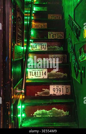 TOKYO - november 19, 2023: Rustic stairs illuminated by green neon and adorned with old license plates Stock Photo