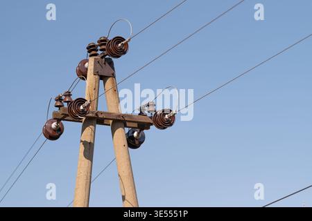 Close view of electric lines connection, visible clamps and brackets joining multiple conductors, sharp shadows and maintenanceready technical framing Stock Photo