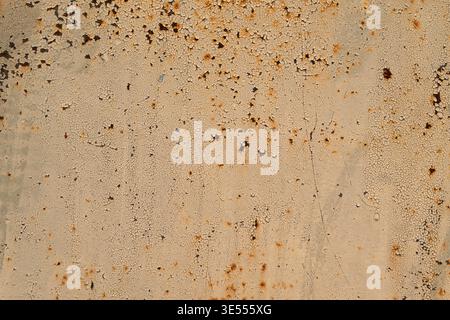 Speckled rust pattern on metal sheet with dense pinprick dots, subtle orangebrown flecks on pale field, quiet minimalist texture ideal for backgrounds Stock Photo