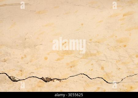 Faded stucco wall featuring horizontal crack, soft beige tones with subtle speckled patina and gentle surface imperfections, quiet nostalgic atmospher Stock Photo