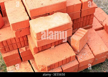 Stack of red ceramic bricks on a wooden pallet at a construction site. Building materials for masonry work, house renovation, and industrial architect Stock Photo