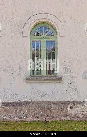 Old arched window with a green-painted wooden frame set into a rustic wall, Muhu, Estonia, Europe. Stock Photo
