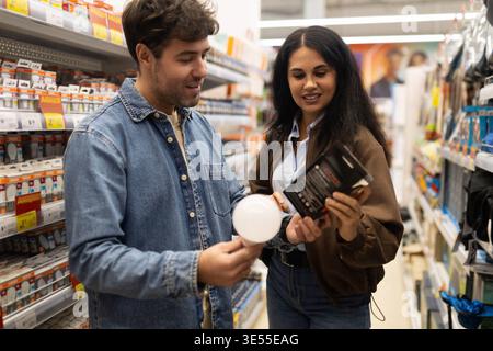 Couple comparing light bulbs, making a purchase decision in a retail aisle Stock Photo