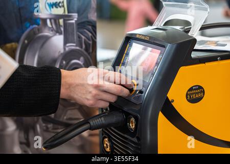 Close-up of a person operating the digital interface of a Weco MicroPulse 225 professional welding machine at a trade show, highlighting advanced Stock Photo