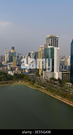 Bangkok, Thailand - 05 February 2026: Aerial view of Benjakitti Forest Park with its large lake, surrounded by modern skyscrapers and a busy road unde Stock Photo