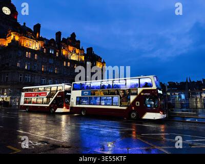 Edinburgh, Scotland, UK - February 15, 2026: Double decker buses on a rainy Edinburgh evening with glowing historic architecture, wet reflections and Stock Photo