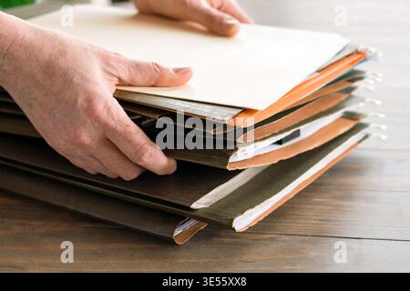 Closeup person hands grabbing file folders from stack on desk. Papers and documents visible, highlighting organization, filing, and everyday administr Stock Photo