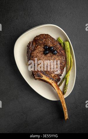 Grilled tomahawk steak with asparagus on plate Stock Photo