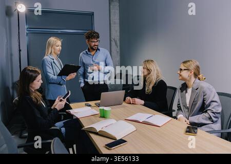 Diverse business colleagues holding a team meeting, discussing ideas and planning projects in a modern shared office space Stock Photo