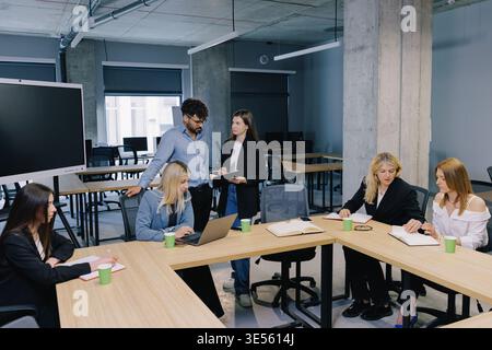 Business professionals communicating and brainstorming during a corporate meeting in a contemporary workspace. Team members collaborating on projects Stock Photo