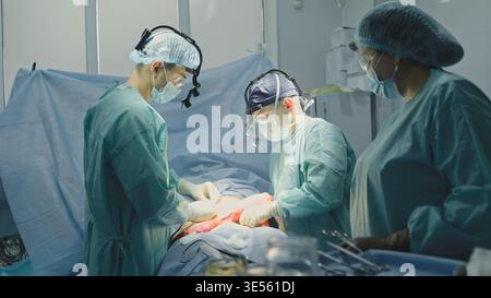 Medical group team of professional surgeons operating patient innovative organ transplantation in modern clinic three doctors interns practitioners Stock Photo