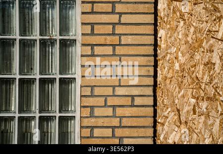 old building with brick walls and a window covered with OSB panels Stock Photo