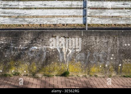 Old concrete wall with cracks, structures and a white wooden fence Stock Photo