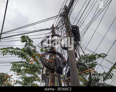 Messy electrical wires and tangled cables on a wall. Concept of poor cable management and electrical safety hazards Stock Photo