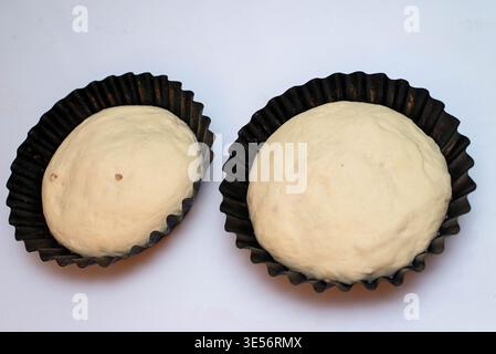 Raw dough prepared for traditional Easter bread placed in baking molds on light background. Homemade baking concept. Stock Photo