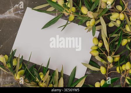Premium olive oil branding mockup with fresh green olives on marble. Blank white card for logo text Stock Photo