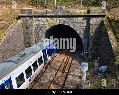 Derbyshire, UK - Mar 26 2026: Passenger train entering Totley Tunnel in Derbyshire UK beneath a historic stone portal, with a dramatic railway scene in bright daylight Stock Photo