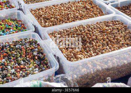 Assorted nuts and colorful sweets in plastic boxes at market healthy snacks variety food display concept Stock Photo
