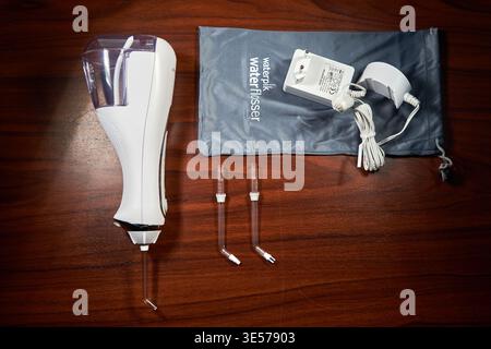 A top-down flat lay photograph of a Waterpik cordless water flosser dental care set arranged on a dark polished wooden surface. The main unit is Stock Photo